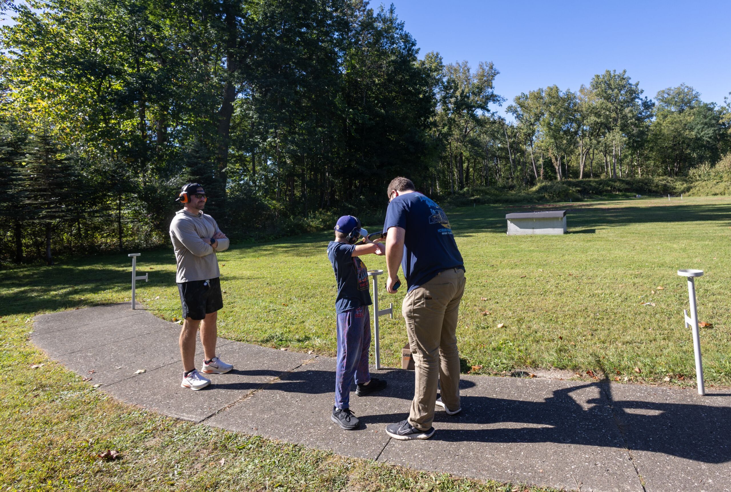 2026Sept26-047 Ryan M. getting trap instruction from a mentor with dad looking on.