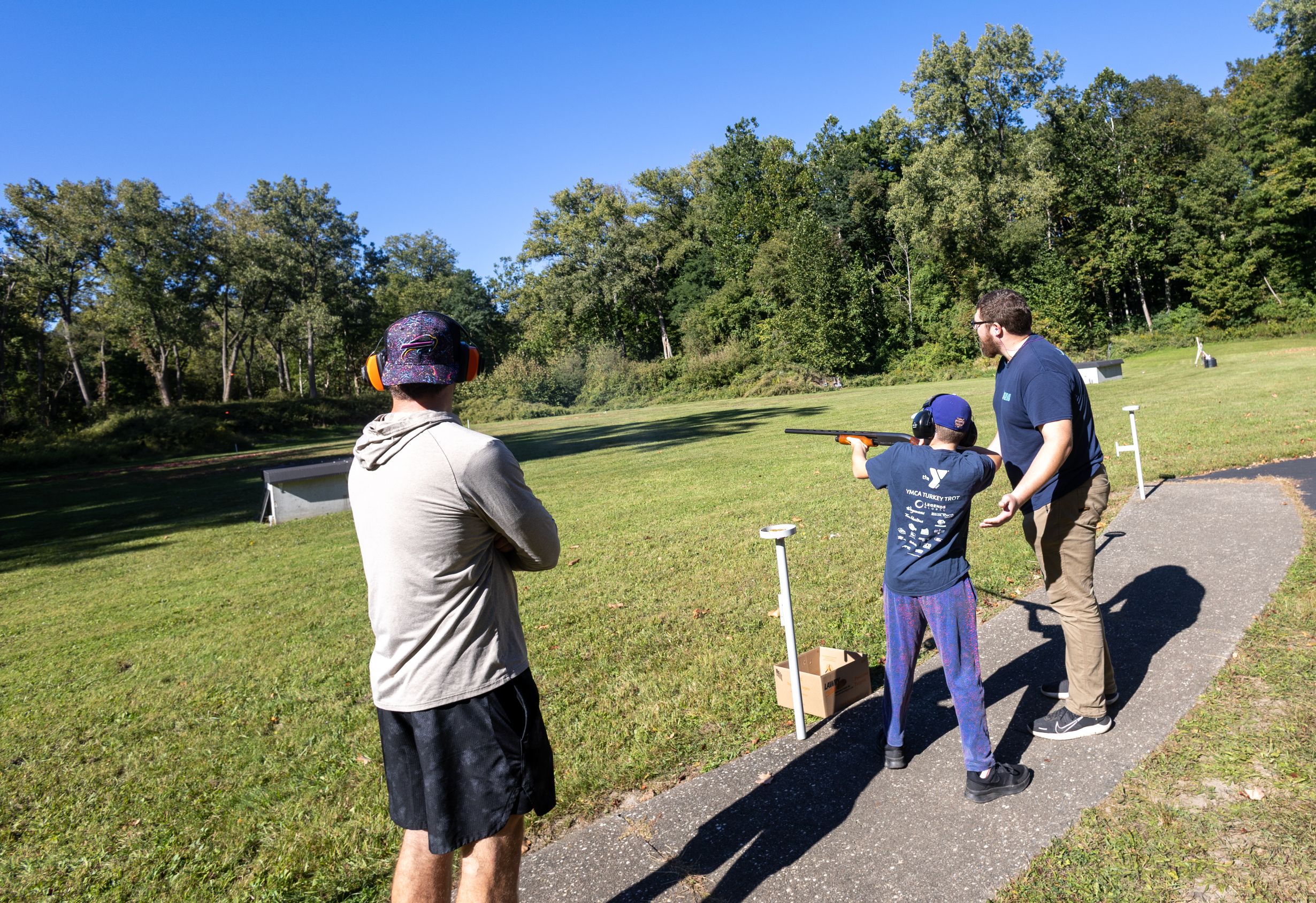 2026Sept26-049 Ryan M. getting trap instruction from a mentor with dad looking on.